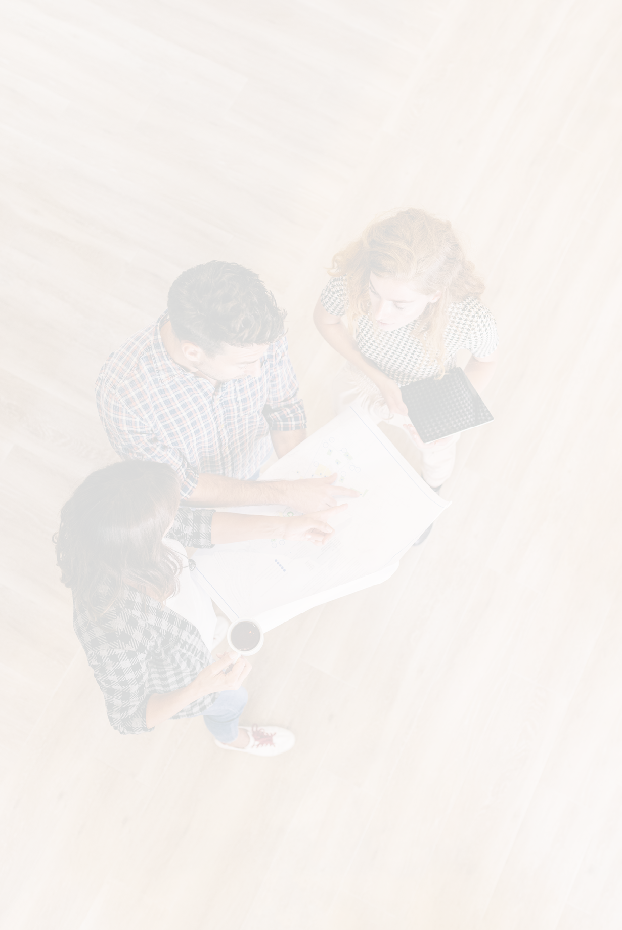 Creative architects on casual meeting reviewing blueprints standing on a wooden floor. Top view.