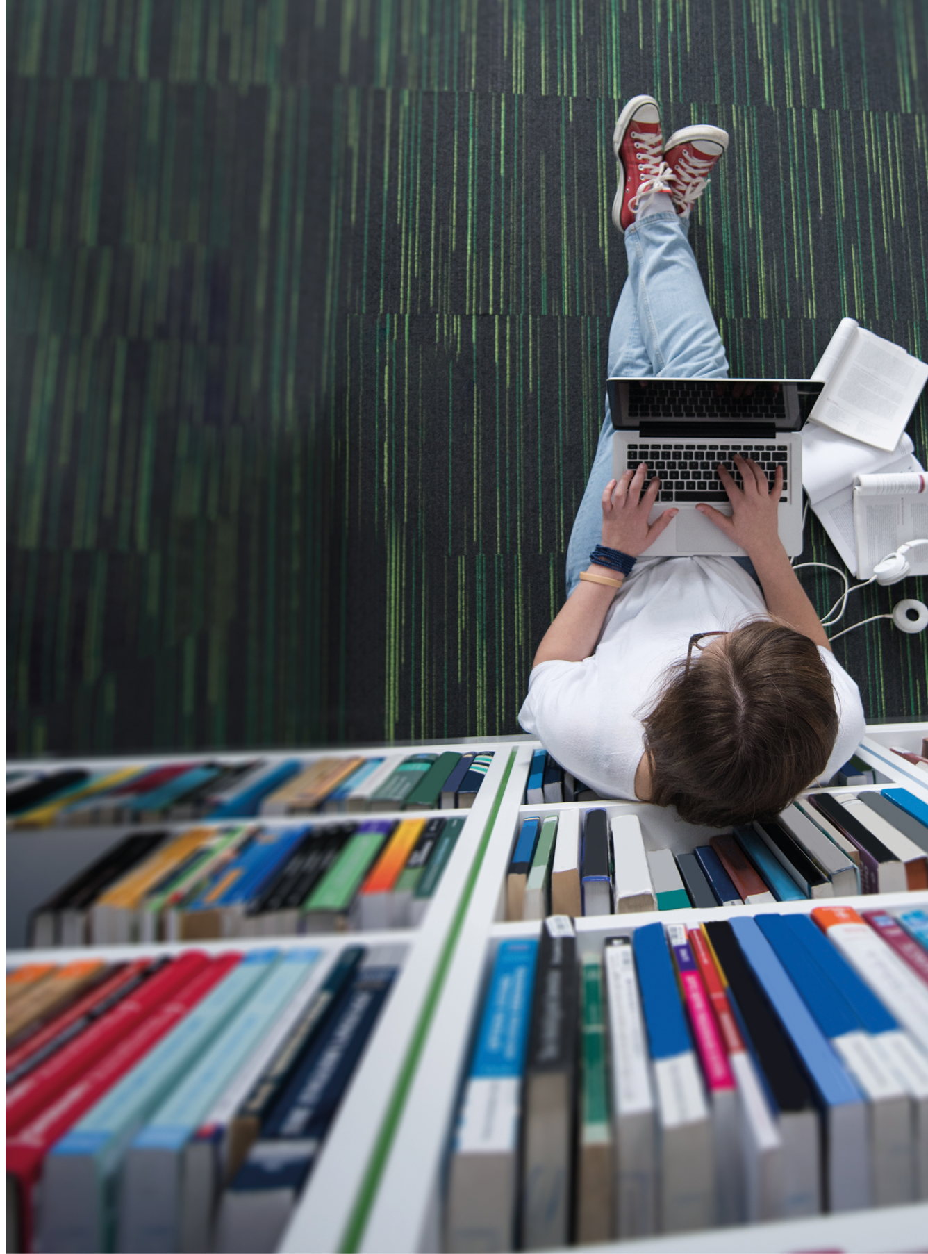 female student study in library using tablet and searching internet while Listening music and lessons on white headphones