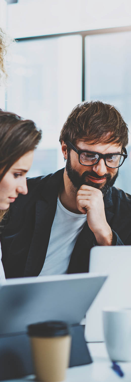 Teamwork concept.Young creative coworkers working with new startup project in modern office.Group of three people analyze data on desktop computer.Horizontal,blurred background