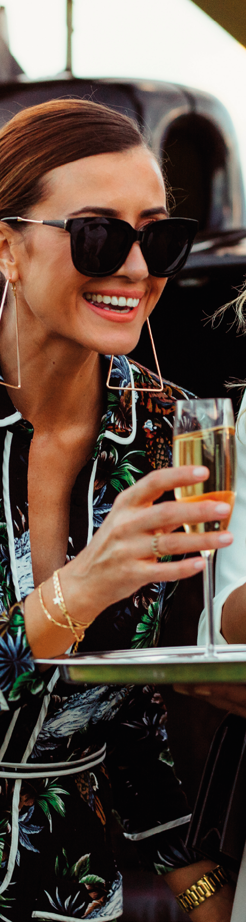 Two beautiful women having welcome drinks served by a male host. Man greets female friends with wine by a helicopter.