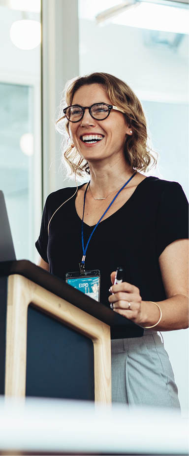 Businesswoman standing at podium with laptop giving a speech. Successful female business professional addressing a seminar.